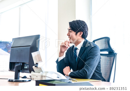 A businessman staring at a PC monitor with a serious expression 89231351
