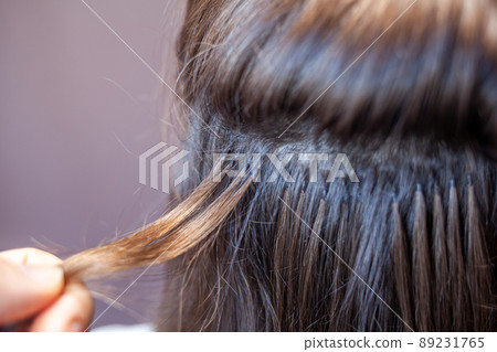Bundles of hair extensions on a woman's head. Hair extensions to thicken your own. Individual strands of hair close-up Bundles of hair extensions on a woman's head. Hair extensions to thicken your own. Individual strands of hair close-up 89231765