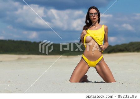 Sensual woman kneeling on beach 89232199