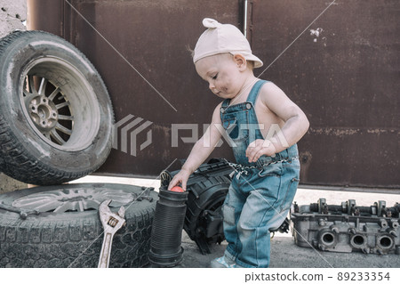 one year old baby playing mechanic among auto parts 89233354
