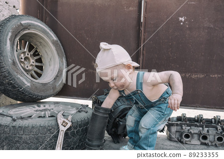 one year old baby playing mechanic among auto parts one year old baby playing mechanic among auto parts 89233355