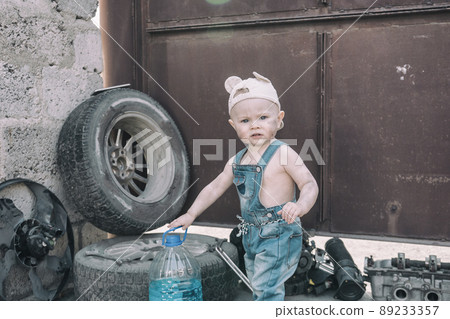 one year old baby playing mechanic among auto parts 89233357