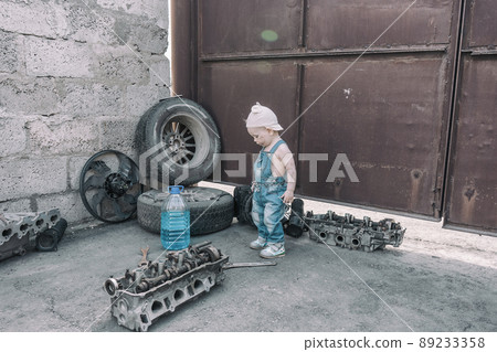 one year old baby playing mechanic among auto parts 89233358
