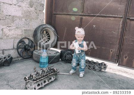 one year old baby playing mechanic among auto parts 89233359