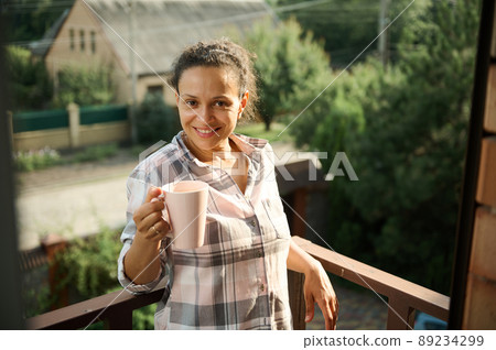 Charming woman relaxing on the balcony of a private house in a small village 89234299
