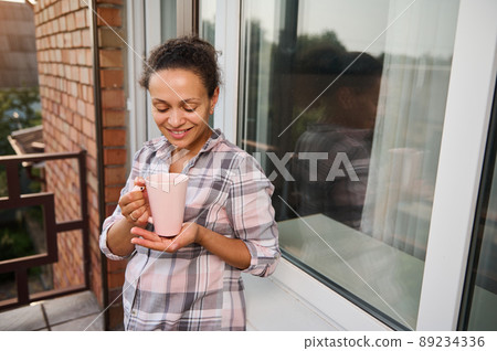 Attractive young woman enjoying vacations and drinking coffee on hotel balcony 89234336