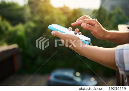 Close-up of woman hands holding mobile phone against sunlight background Close-up of woman hands holding mobile phone against sunlight background 89234359