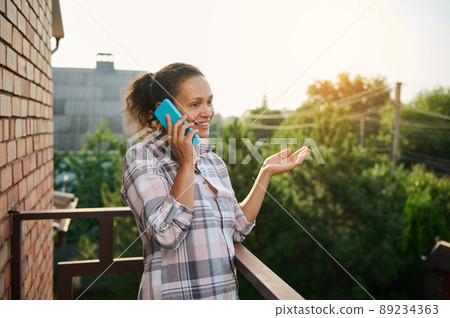 Beautiful woman talking on mobile phone on the balcony 89234363
