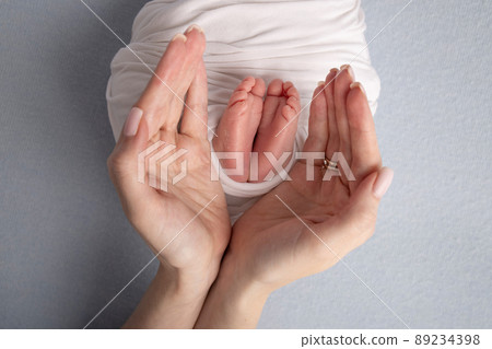 The palms of the father, the mother are holding the foot of the newborn baby. Feet of the newborn on the palms. 89234398