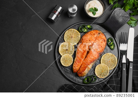 Delicious roasted fish served on black table, flat lay. Space for text Delicious roasted fish served on black table, flat lay. Space for text 89235001