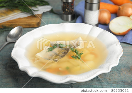 Delicious fish soup in bowl on blue wooden table Delicious fish soup in bowl on blue wooden table 89235031