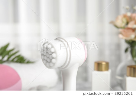 Modern face cleansing brush on blurred background. Cosmetic accessory 89235261