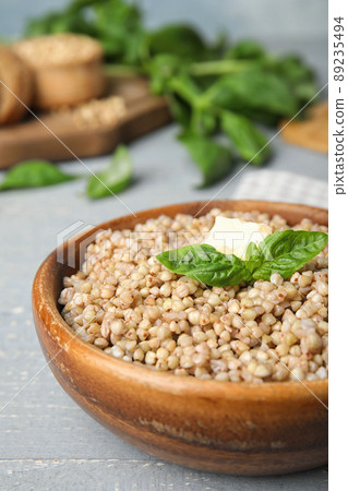 Tasty buckwheat porridge with butter on grey wooden table, closeup 89235494