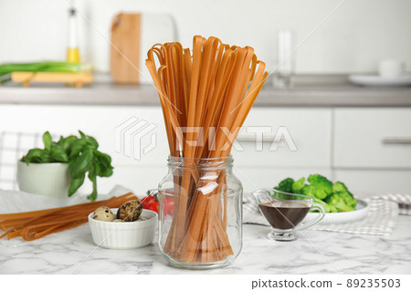 Uncooked buckwheat noodles and fresh ingredients on white marble table in kitchen Uncooked buckwheat noodles and fresh ingredients on white marble table in kitchen 89235503
