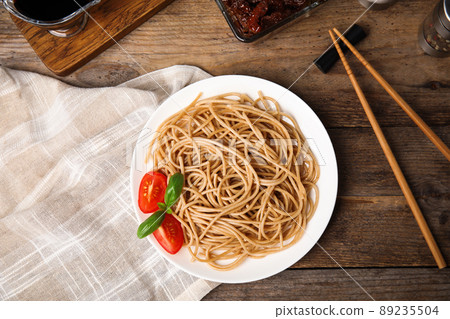 Tasty buckwheat noodles with chopsticks on wooden table, flat lay Tasty buckwheat noodles with chopsticks on wooden table, flat lay 89235504