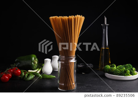 Uncooked buckwheat noodles and fresh ingredients on black table Uncooked buckwheat noodles and fresh ingredients on black table 89235506