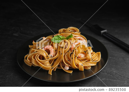 Tasty buckwheat noodles with shrimps on black table Tasty buckwheat noodles with shrimps on black table 89235508
