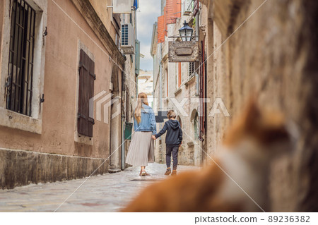 Mom and son travelers enjoying Colorful street in Old town of Kotor on a sunny day, Montenegro. Travel to Montenegro concept Mom and son travelers enjoying Colorful street in Old town of Kotor on a sunny day, Montenegro. Travel to Montenegro concept 89236382