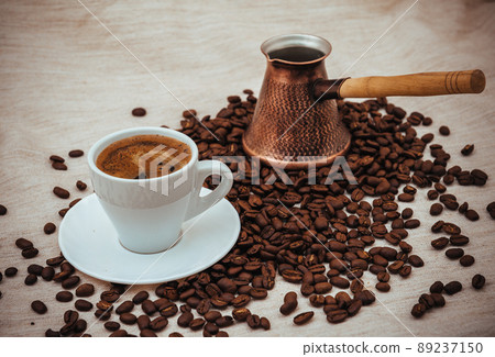 Coffee turk and cup of coffee on burlap background. coffee beans isolated on white background. roasted coffee beans Coffee turk and cup of coffee on burlap background. coffee beans isolated on white background. roasted coffee beans 89237150