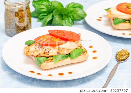 Open-face sandwich with chicken, mozzarella, tomato, pesto and basil on toasted ciabatta, horizontal 89237707