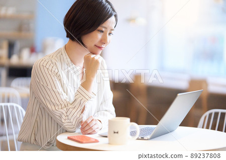 一位年輕女子在咖啡館裡盯著電腦屏幕 一位年輕女子在咖啡館裡盯著電腦屏幕 89237808