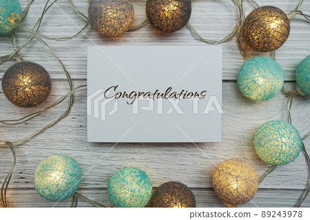 Congrats text on paper card with LED cotton balls top view on wooden background Congrats text on paper card with LED cotton balls top view on wooden background 89243978