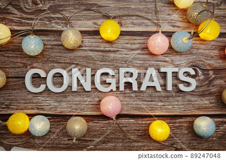 Congrats text with LED cotton balls decoration on wooden background Congrats text with LED cotton balls decoration on wooden background 89247048
