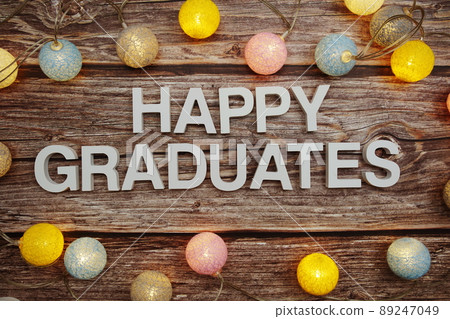 Happy Graduation text with LED cotton balls decoration on wooden background Happy Graduation text with LED cotton balls decoration on wooden background 89247049