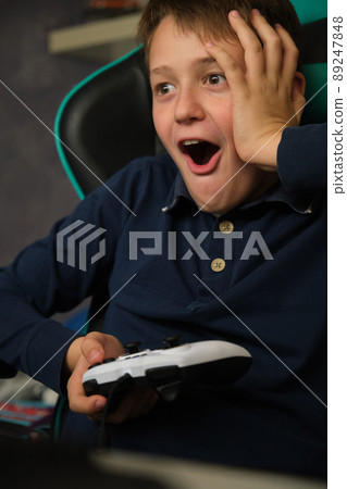 the boy is playing a video game console 89247848