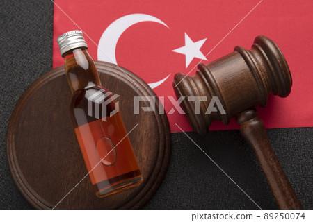 Bottle of alcohol and wooden gavel as symbol of law on Turkey flag background. Top view close up. Alcohol legislation in Turkey. Bottle of alcohol and wooden gavel as symbol of law on Turkey flag background. Top view close up. Alcohol legislation in Turkey. 89250074