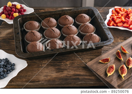 Homemade chocolate cupcakes and seasonal berries for decor. Process of making muffins with fruit. Homemade chocolate cupcakes and seasonal berries for decor. Process of making muffins with fruit. 89250076