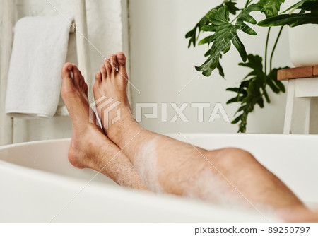 Close-up of man lying in bath with foam and relaxing during spa procedure Close-up of man lying in bath with foam and relaxing during spa procedure 89250797