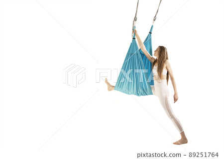 Slim woman engaged in class of aero yoga in hammocks antigravity isolated on white background. Aerial gymnastics. Slim woman engaged in class of aero yoga in hammocks antigravity isolated on white background. Aerial gymnastics. 89251764