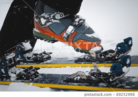 Close-up of freeride ski boots on snow. Skitour concept. Used worn boots on a male skier against the background of a glacier in cloudy weather in the mountains Close-up of freeride ski boots on snow. Skitour concept. Used worn boots on a male skier against the background of a glacier in cloudy weather in the mountains 89252998