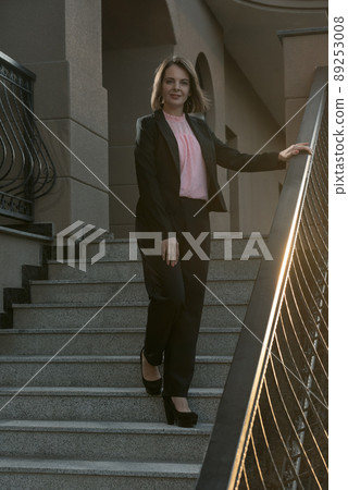 Successful woman in business clothing ot the stairs. Woman wearing black suit. Young business woman Successful woman in business clothing ot the stairs. Woman wearing black suit. Young business woman 89253008