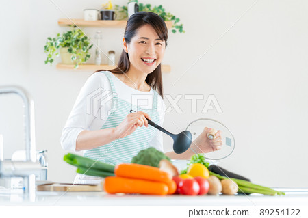 Smiley middle woman cooking in the kitchen Smiley middle woman cooking in the kitchen 89254122