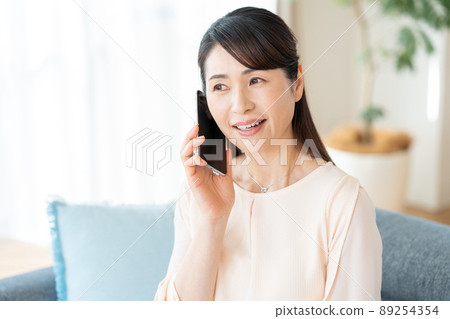 中間女人在房間裡操作智能手機 中間女人在房間裡操作智能手機 89254354