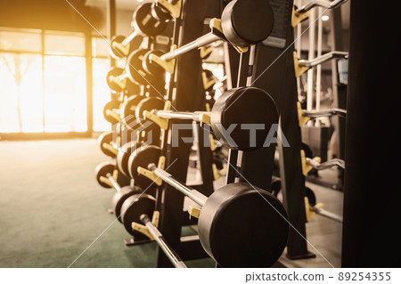 Close up row of barbells dumbbells in modern sports club with soft light. 89254355