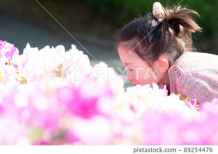 一個女孩嗅著花的香味 89254476