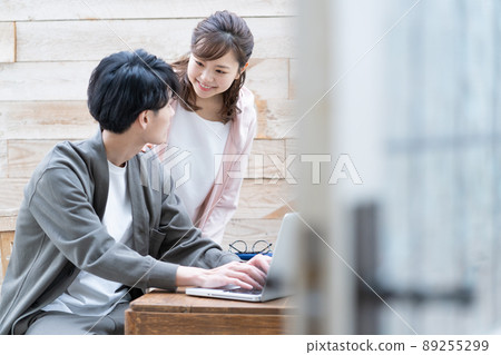 一個遠程工作的年輕人和他的妻子在她身邊看著 89255299
