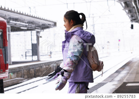 一個在寒假或冬季家庭旅行的雪天在車站站台上對雪感到高興的女孩 89255783