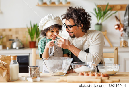 Cheerful black father and son cooking and having fun Cheerful black father and son cooking and having fun 89256044
