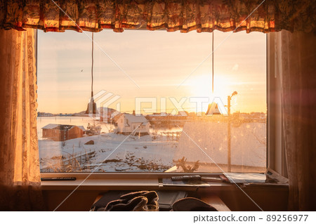View from curtain window with sunset over snowy village on coastline in winter View from curtain window with sunset over snowy village on coastline in winter 89256977