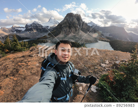 Young asian male traveler taking selfie portrait on the hill with mount assiniboine in national park 89256983