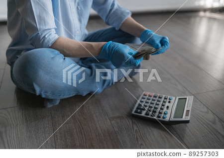 A businesswoman finds a wad of money sitting on the floor. Next to the floor is a calculator. Medical business 89257303