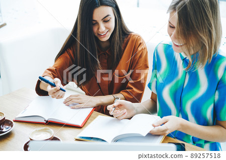 Students doing homework together in cafe Students doing homework together in cafe 89257518