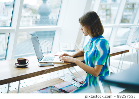 Thoughtful female freelancer working on laptop 89257555