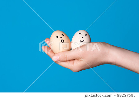 Hand holding two easter eggs with a funny face drawn on it. Easter or healthy diet eating concept. Hand holding two easter eggs with a funny face drawn on it. Easter or healthy diet eating concept. 89257593