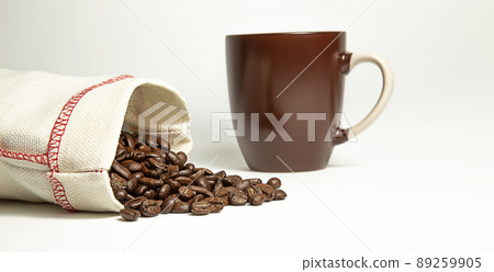 Coffee beans spilled out of the bag on a white background. Brown mug. Isolate. Coffee beans spilled out of the bag on a white background. Brown mug. Isolate. 89259905