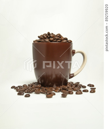Coffee beans spilled out of the brown mug. On a white background. Coffee beans spilled out of the brown mug. On a white background. 89259920